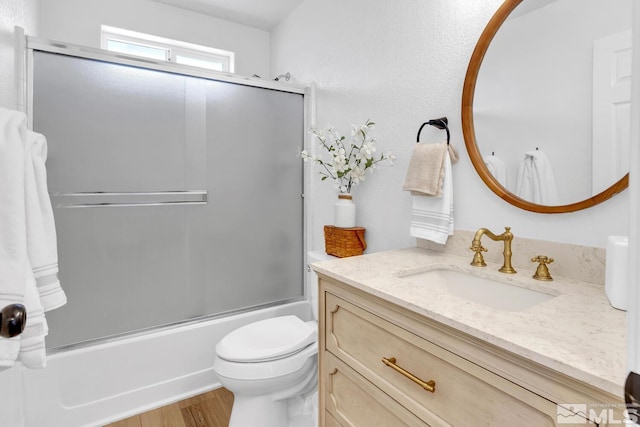 full bathroom featuring vanity, wood-type flooring, shower / bath combination with glass door, and toilet