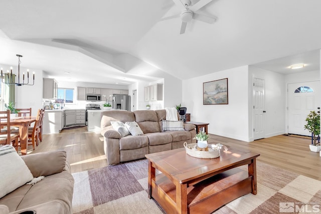 living room featuring vaulted ceiling, sink, ceiling fan with notable chandelier, and light hardwood / wood-style flooring