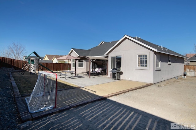 rear view of property featuring a playground and a patio