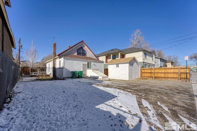 snow covered rear of property featuring a storage shed