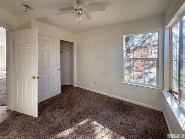 unfurnished bedroom featuring dark carpet, a closet, and ceiling fan