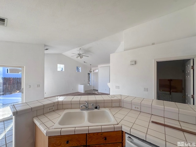 kitchen featuring vaulted ceiling, plenty of natural light, tile countertops, and sink