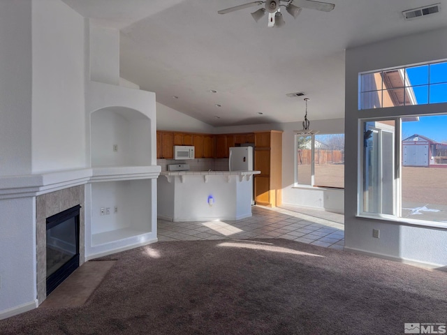 unfurnished living room with lofted ceiling, a fireplace, light colored carpet, and ceiling fan