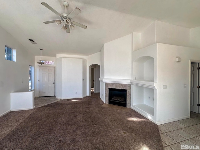 unfurnished living room with ceiling fan, carpet flooring, vaulted ceiling, and a tile fireplace