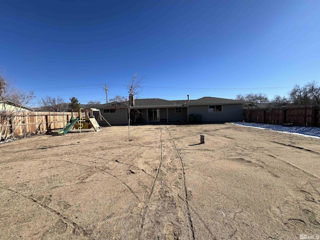 rear view of property with a playground