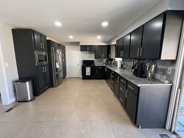 kitchen with light tile patterned floors, light stone countertops, sink, and black appliances