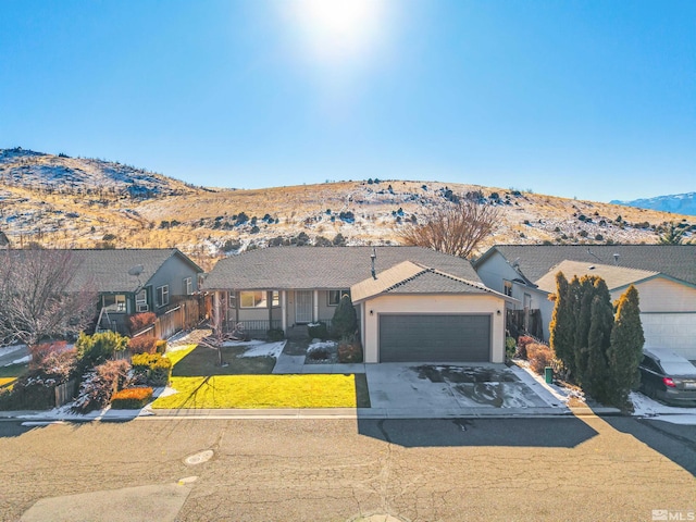 ranch-style home featuring a garage, a mountain view, and a front lawn