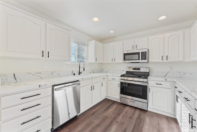 kitchen with sink, stainless steel appliances, dark hardwood / wood-style floors, light stone counters, and white cabinets