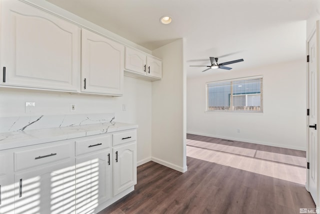 kitchen featuring light stone counters, ceiling fan, dark wood-type flooring, and white cabinets