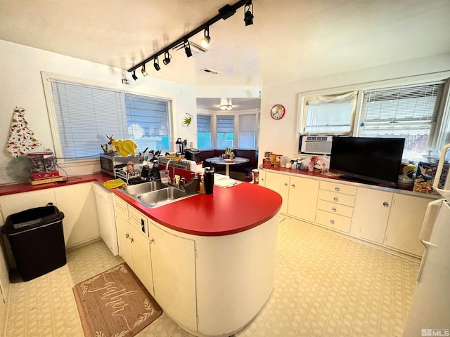 kitchen with white cabinetry, kitchen peninsula, sink, and cooling unit