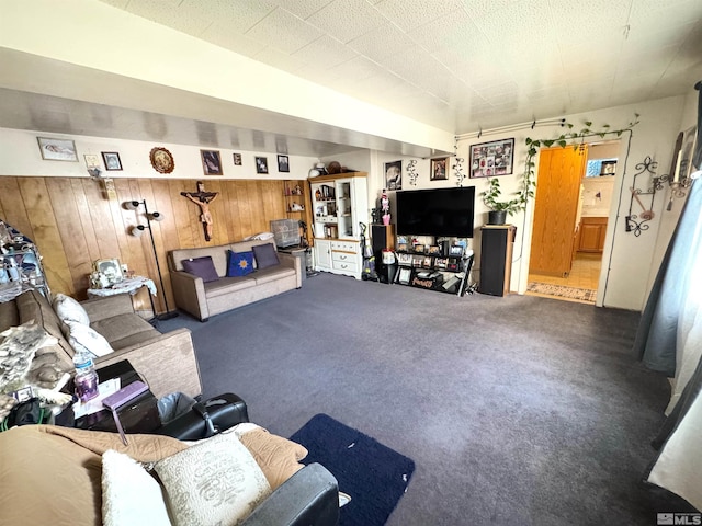 living room with dark carpet and wood walls