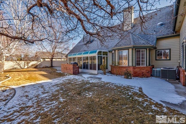 snow covered house featuring a sunroom and central air condition unit