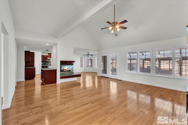 unfurnished living room featuring light wood-type flooring, high vaulted ceiling, ceiling fan, and a multi sided fireplace