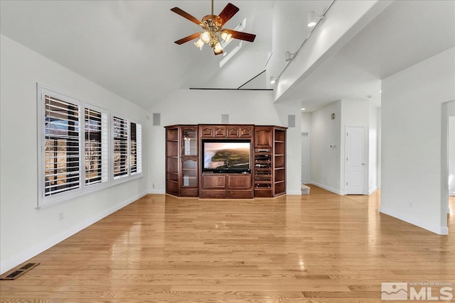 unfurnished living room with ceiling fan, rail lighting, high vaulted ceiling, and light wood-type flooring