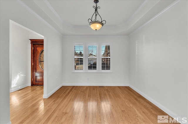 unfurnished room featuring crown molding, a tray ceiling, and light wood-type flooring