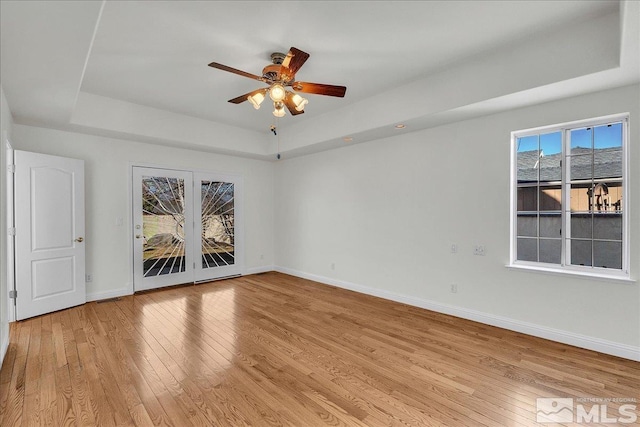 unfurnished room with light hardwood / wood-style floors, a raised ceiling, and ceiling fan