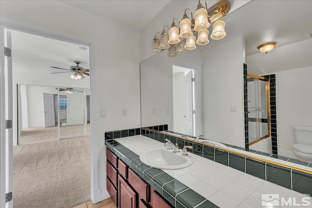 full bathroom with ceiling fan, enclosed tub / shower combo, vanity, and toilet