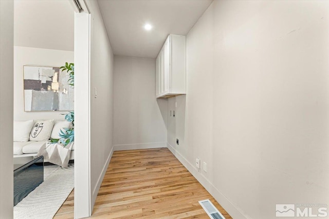 clothes washing area with light hardwood / wood-style flooring