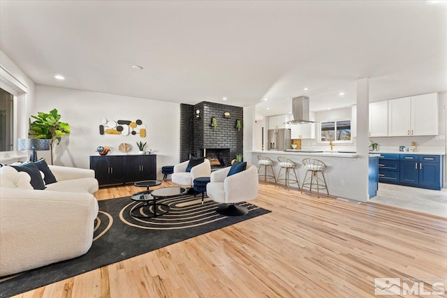 living room featuring a brick fireplace and light wood-type flooring