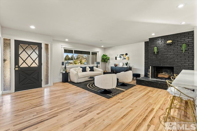 living room with hardwood / wood-style flooring and a brick fireplace