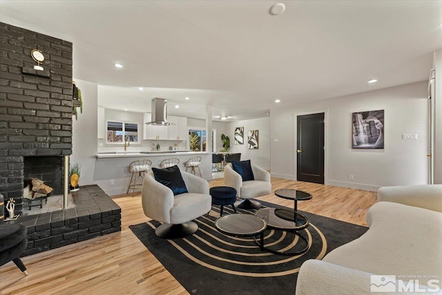 living room featuring a brick fireplace and light wood-type flooring