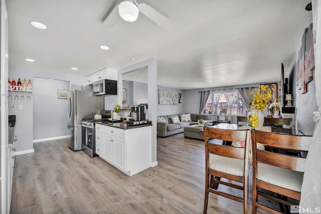 kitchen with ceiling fan, appliances with stainless steel finishes, white cabinets, and light hardwood / wood-style floors