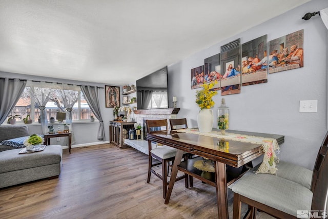 dining room with hardwood / wood-style floors and a brick fireplace