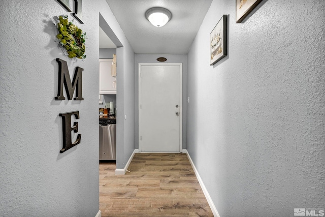 hallway featuring light hardwood / wood-style floors and a textured ceiling