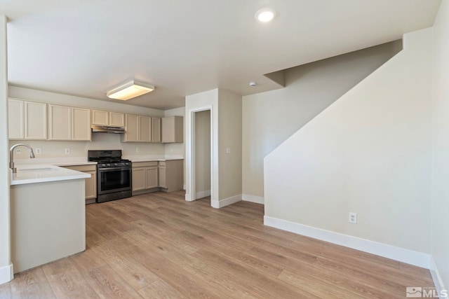 kitchen featuring gas range, sink, light hardwood / wood-style floors, and kitchen peninsula