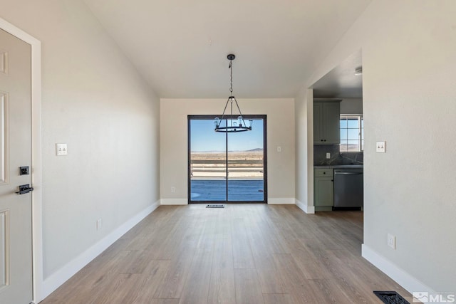 unfurnished dining area featuring a chandelier and light hardwood / wood-style floors