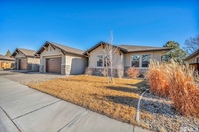 view of front of property with a front yard, driveway, an attached garage, stone siding, and board and batten siding