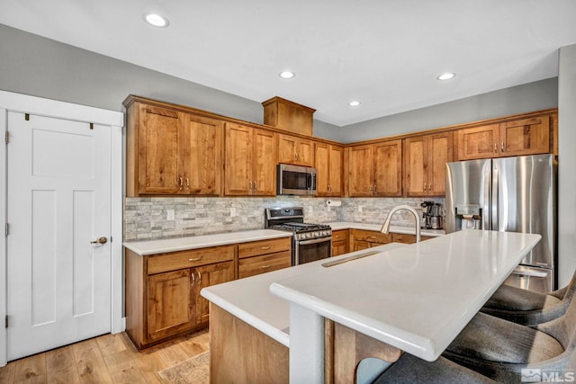 kitchen with a sink, stainless steel appliances, brown cabinets, and light countertops