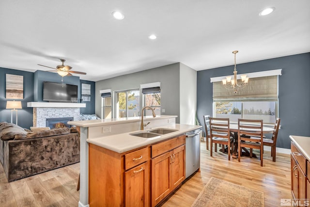 kitchen featuring stainless steel dishwasher, light wood-type flooring, light countertops, and a sink