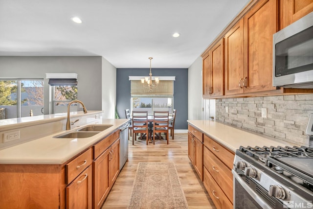 kitchen featuring light wood-style flooring, a healthy amount of sunlight, appliances with stainless steel finishes, and a sink