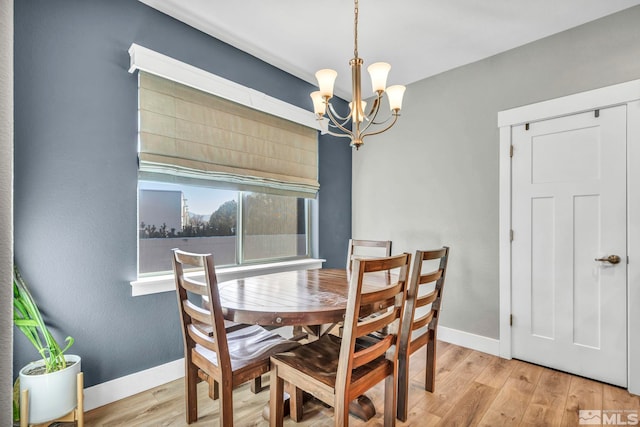 dining area featuring a chandelier, baseboards, and wood finished floors