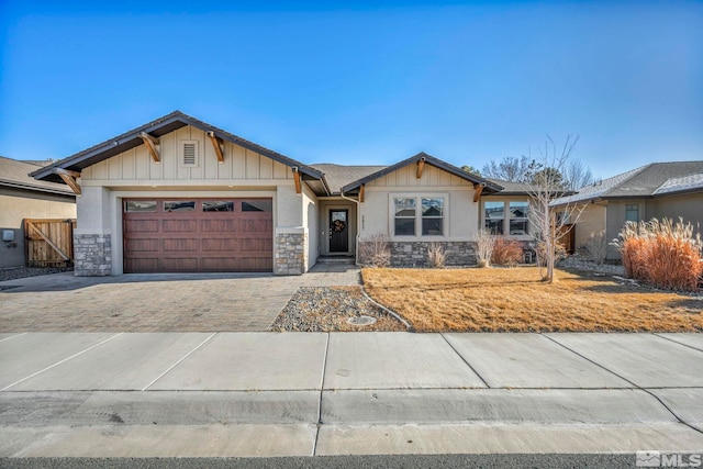 craftsman house featuring decorative driveway, stone siding, and a garage