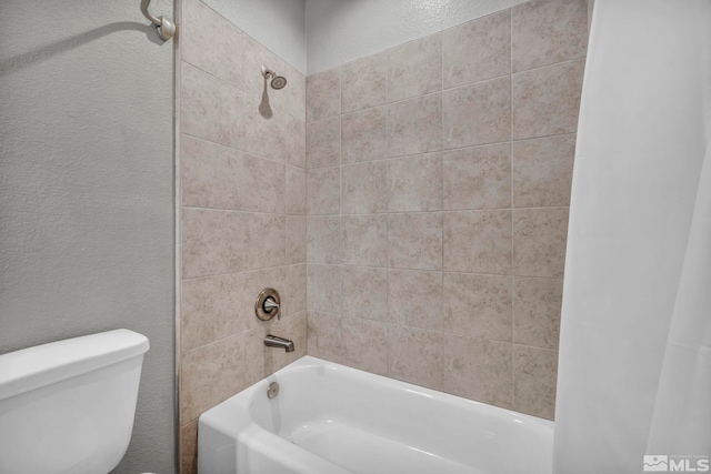 full bath with toilet, shower / bath combination, and a textured wall