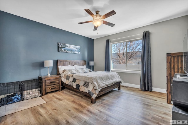 bedroom with a ceiling fan, wood finished floors, and baseboards