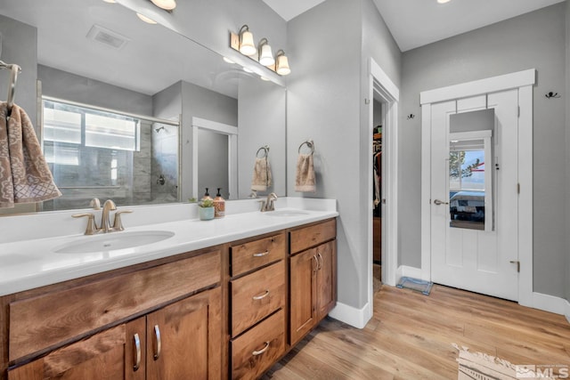 bathroom featuring a sink, visible vents, wood finished floors, and a shower stall