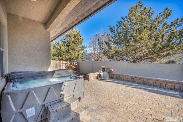 view of patio / terrace featuring a hot tub and a fenced backyard