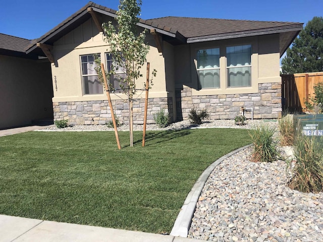 ranch-style home featuring stone siding, stucco siding, a front lawn, and fence