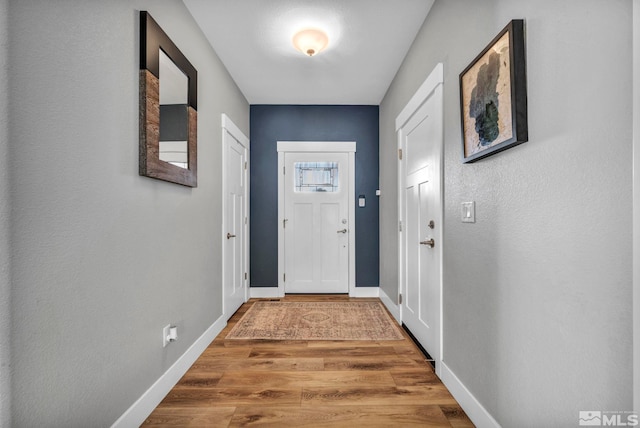 doorway to outside with baseboards and wood finished floors