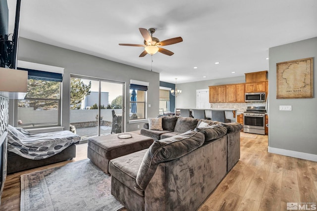 living area with recessed lighting, baseboards, ceiling fan with notable chandelier, and light wood finished floors