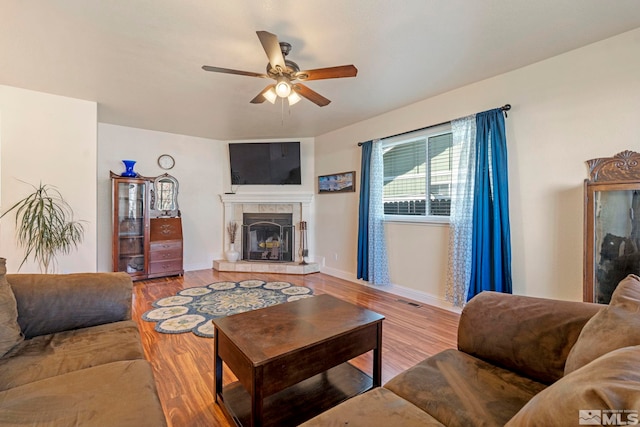 living room featuring ceiling fan, a fireplace, and light hardwood / wood-style flooring