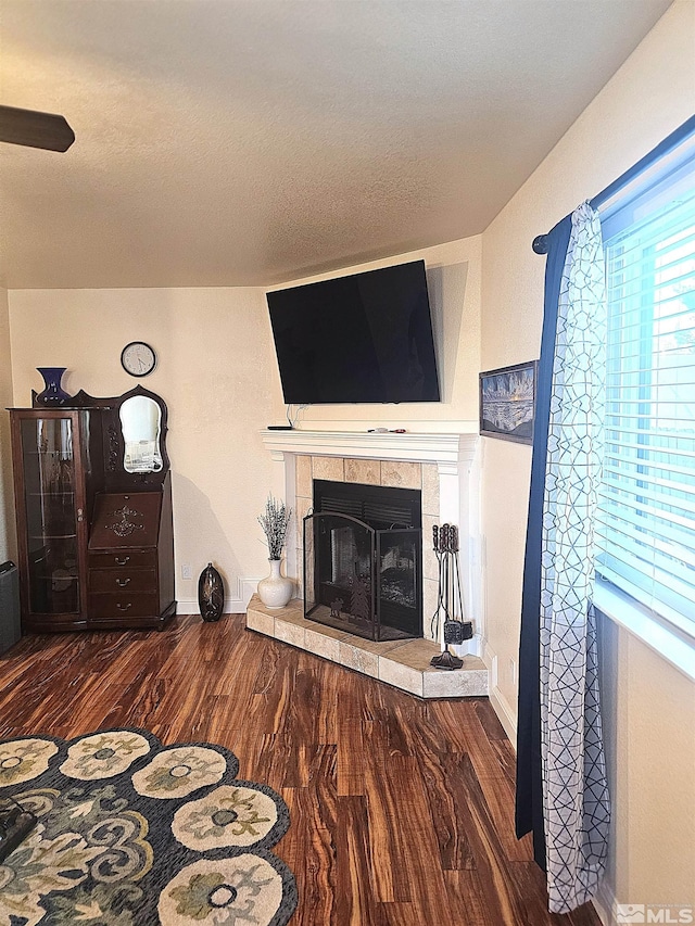 interior space featuring dark wood-type flooring, a tiled fireplace, and a textured ceiling