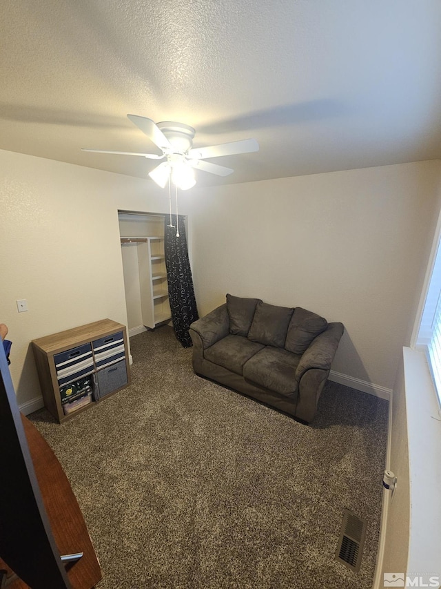 carpeted living room with ceiling fan and a textured ceiling