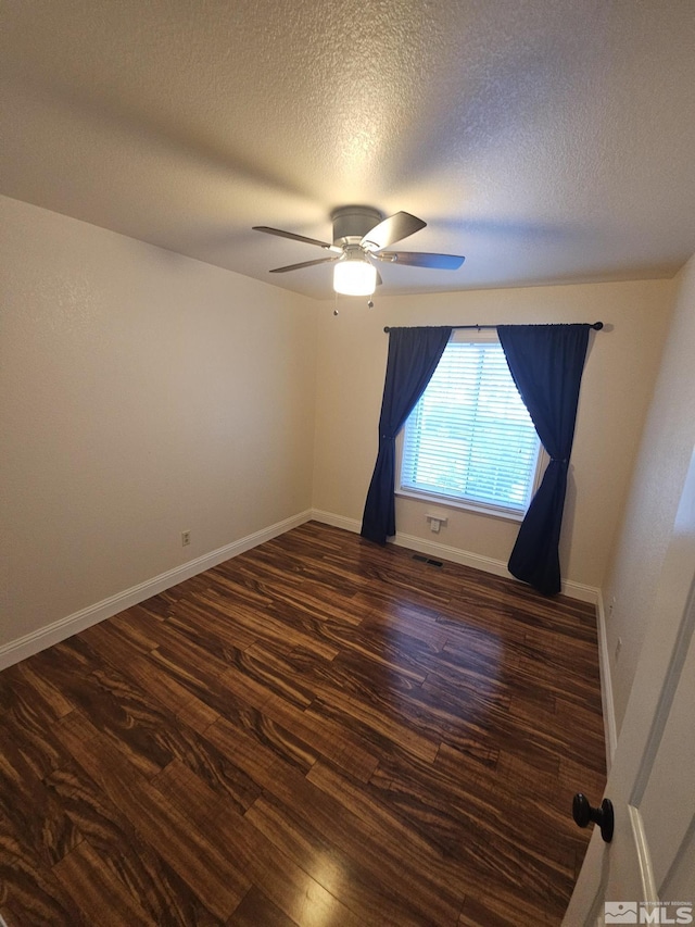 empty room featuring dark hardwood / wood-style flooring, a textured ceiling, and ceiling fan