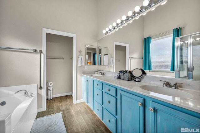 bathroom with a relaxing tiled tub, vanity, and hardwood / wood-style floors