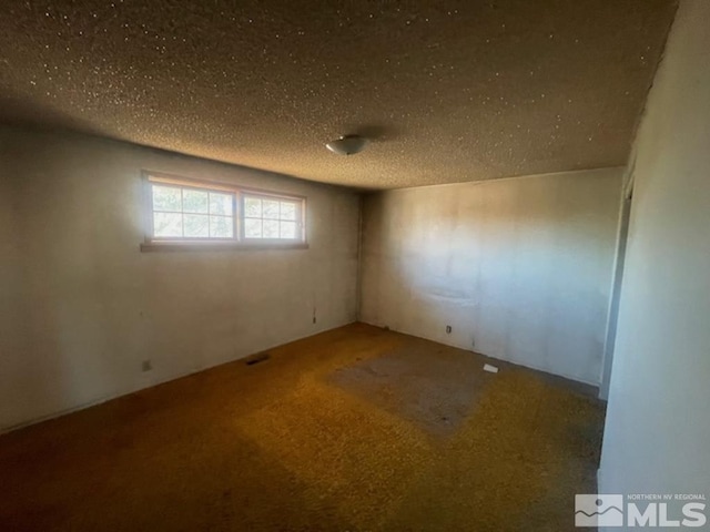 unfurnished room featuring a textured ceiling and carpet