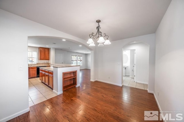 kitchen featuring decorative light fixtures, a chandelier, a center island, black dishwasher, and light hardwood / wood-style floors